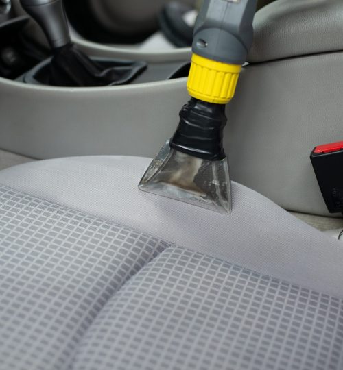 Man car detailing studio worker cleaning car textile upholstery